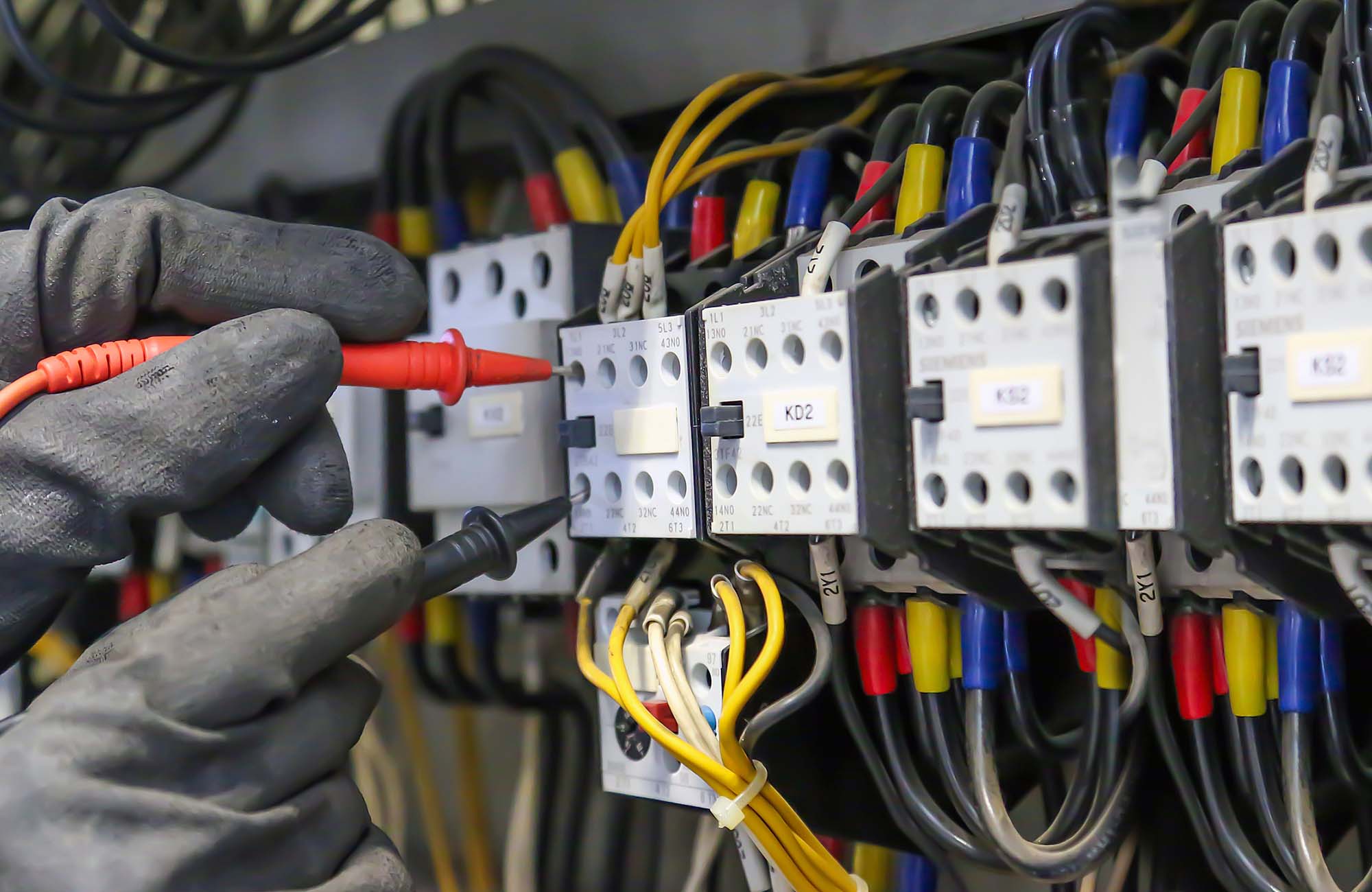 Electrical engineer using digital multi-meter measuring equipment to checking electric current voltage at circuit breaker in main power distribution board