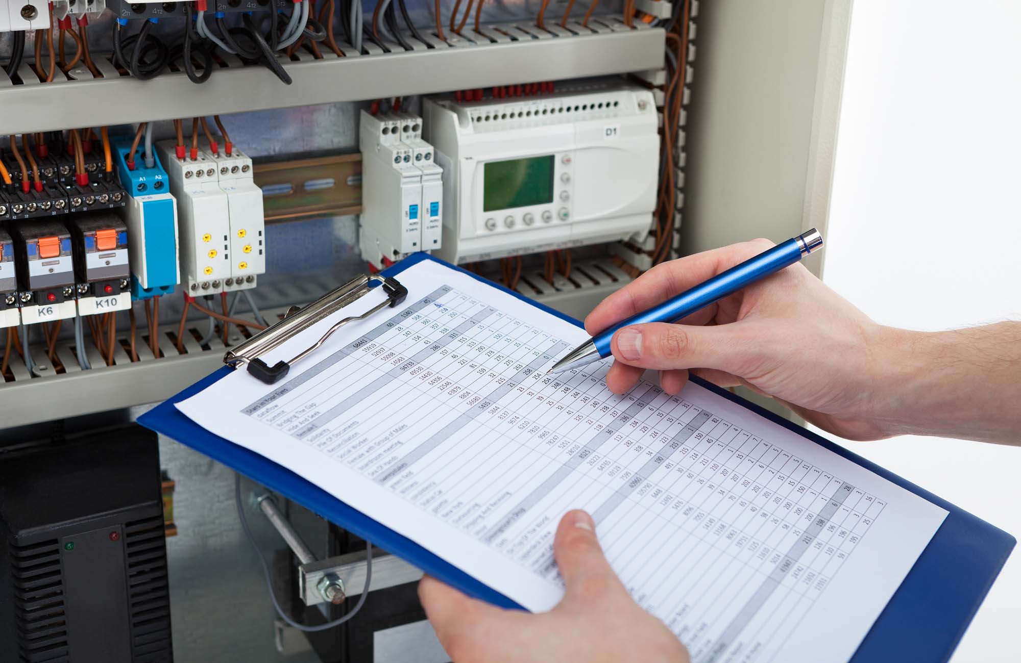 Cropped image of male electrician holding clipboard while examining fusebox